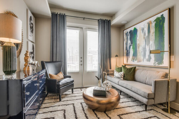 Living room with patterned rug, plush couch, copper coffee table with decor, and framed artwork at The Kathryn townhomes in Frisco.