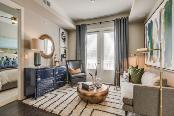 Living room with pattern rug, plush couch, copper coffee table with decor, and framed artwork.
