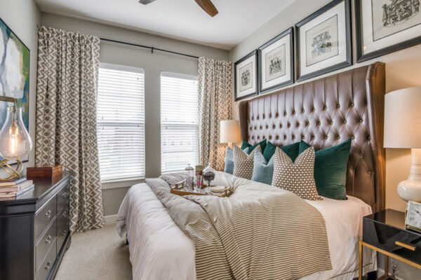 Bedroom with carpet, plush bed with headboard, framed artwork, and bedside tables with lamps.