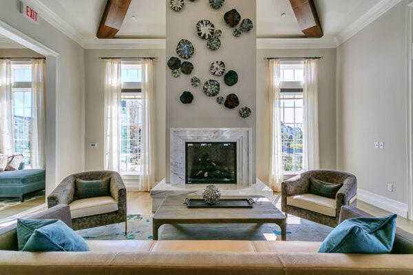 Lounge with plush seating, large coffee table, fireplace, wall decor, and large windows.