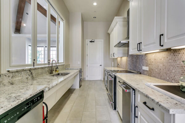 Community kitchen with tile floor, white cabinets, stone counters, and stainless steel appliances.