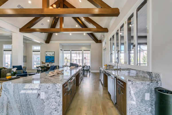 Community kitchen with wood floor and cabinets, stone counters, and stainless steel appliances.
