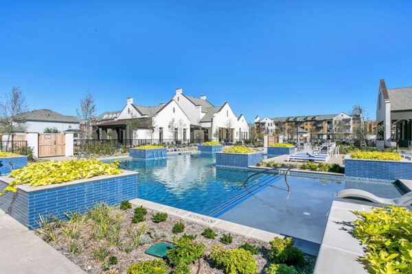 Pool area with lush planters, in-water lounge chairs, and shimmering blue water.