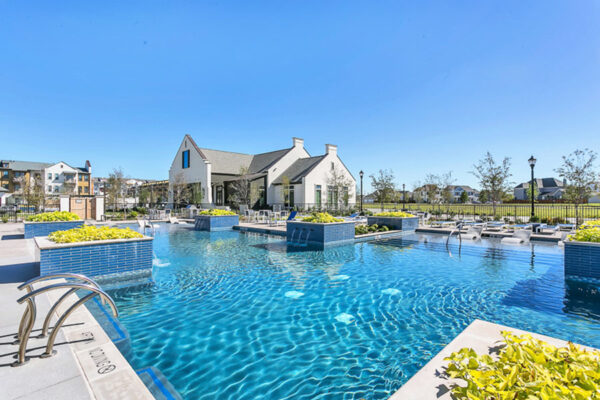 Pool area with lush planters and shimmering blue water at The Kathryn pet-friendly Frisco apartments.