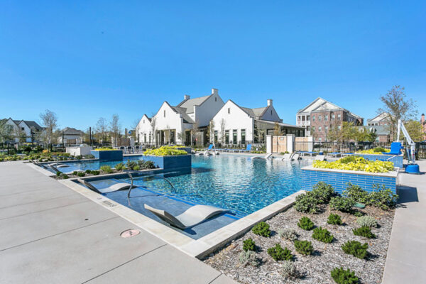 Pool area with in-water lounge chairs, lush planters, and elegant clubhouse.