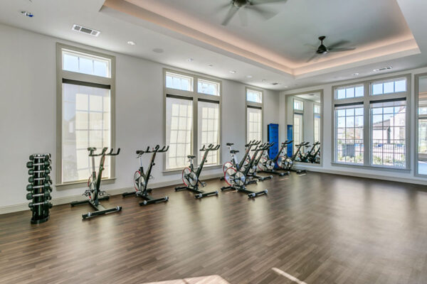 Spin room with wood style floor, spin bikes, and large windows.
