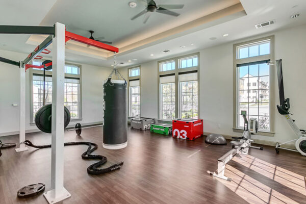 Fitness center with cardio machines, training equipment, and large windows.
