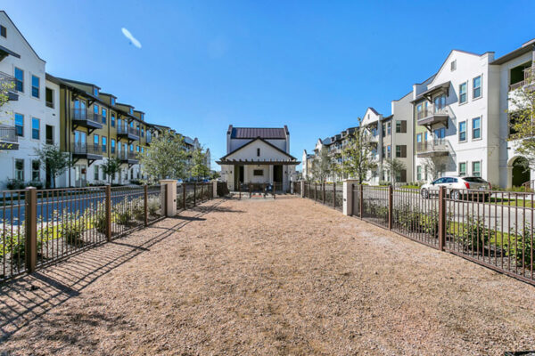Outdoor courtyard with lush landscaping and metal fence.