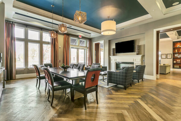 Lounge with herringbone floor, plush seating, large dining table, and fireplace with TV.