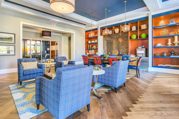Clubroom with herringbone floor, plush seating, and colorful shelves with decor.
