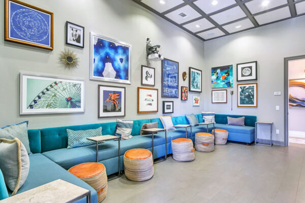 Theater room with large sectional couch, plush ottomans, and lots of framed wall art.