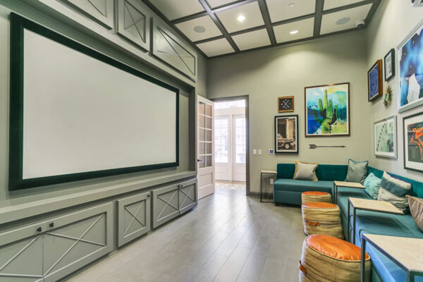 Theater room with large sectional, plush ottomans, and large projection screen.