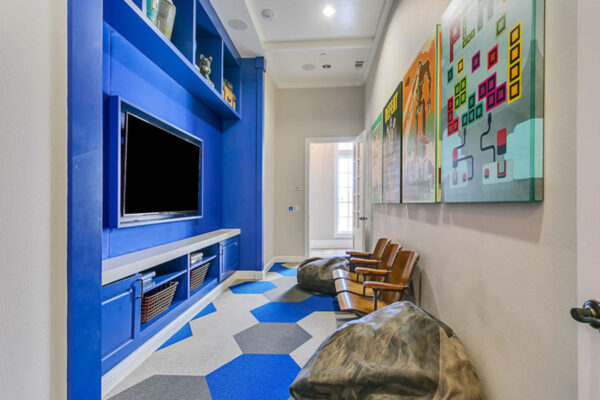 Kids theater room with wood theater seats, bean bag chairs, wall mounted TV, and colorful art.