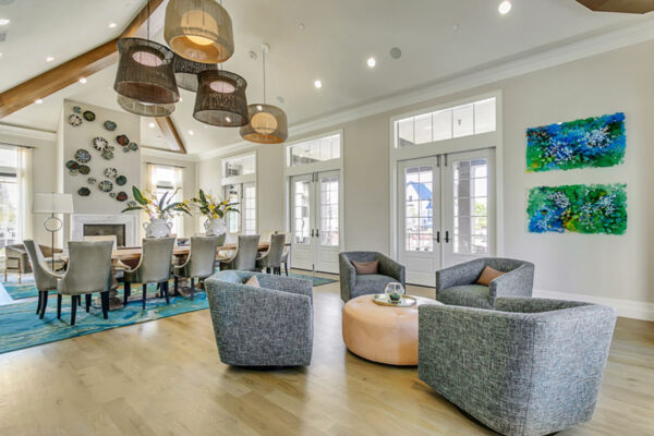 Lounge with wood floor, plush seating, large dining table, wall art, and large windows.