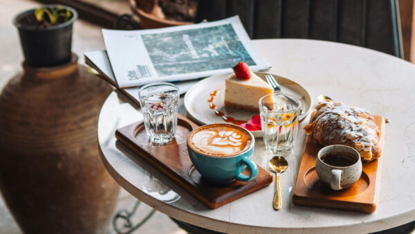 Cafe table with magazines, coffee, and pastries.