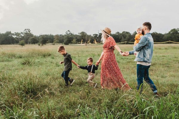 Family with young children walking together in grassy field.