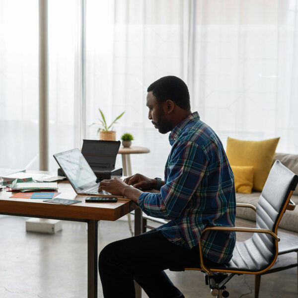 Person working on laptop computer at table in comfortable apartment.